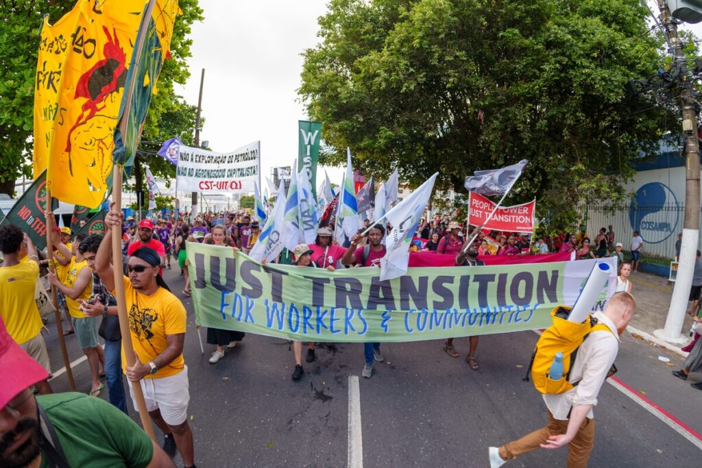 Protesters march for Just Transition holding signs and banners advocating for workers' rights and environmental justice.